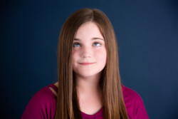 Redhead preteen girl rolling her eyes in front of blue background in Ocoee Florida