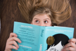 Blonde preteen girl with brown eyes laying on floor reading a book in Winter Garden, Florida