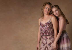 Blonde mother and daughter dressed in shades of purple in front of a golden painted background